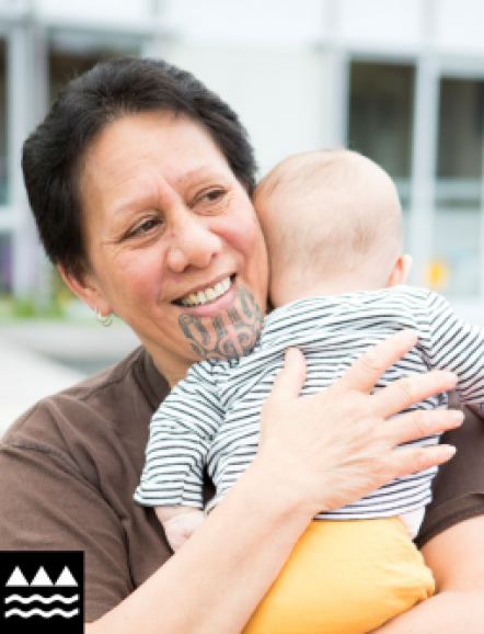 Woman with moko kauae holding a baby.