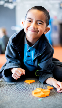 Child sitting on the floor manipulating a maths puzzle.