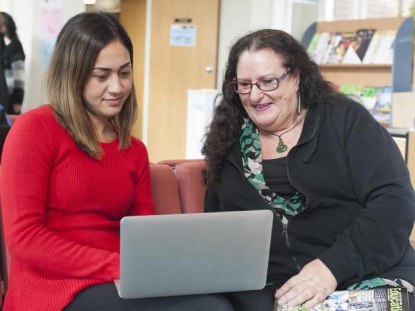 Two teachers looking at a laptop computer together.