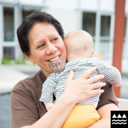 Woman with moko kauae holding a baby.