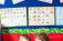 Two children sitting sharing a book under phonics alphabet cards on the wall behind them.